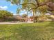 Beautiful grassy backyard with a pool, rock waterfall, and tiki hut, shaded by mature trees at 8970 Lansberry Ct, Las Vegas, NV 89147