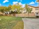 Spacious backyard with a lush green lawn, mature trees, and a concrete pathway at 8970 Lansberry Ct, Las Vegas, NV 89147