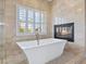 Bathroom featuring a soaking tub, fireplace and window, providing a serene atmosphere at 8970 Lansberry Ct, Las Vegas, NV 89147