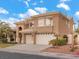 A two-story stucco home with a three car garage, tile roof and manicured landscaping at 8970 Lansberry Ct, Las Vegas, NV 89147