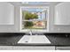 Bright kitchen sink beneath a window with black countertops and modern white cabinets at 8970 Lansberry Ct, Las Vegas, NV 89147