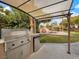 Covered outdoor kitchen with a built-in grill, mini fridge, and bar top overlooking the pool area at 8970 Lansberry Ct, Las Vegas, NV 89147