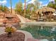 Resort-style pool area with a rock waterfall, waterslide, and a tiki hut for relaxing and entertaining at 8970 Lansberry Ct, Las Vegas, NV 89147