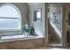 Elegant bathroom featuring a soaking tub beneath a large window and a separate marble shower at 9325 Verlaine Ct, Las Vegas, NV 89145