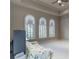 Bright bedroom with neutral tones, ceiling fan, and three arched windows overlooking landscaped outdoors at 9325 Verlaine Ct, Las Vegas, NV 89145