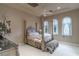 Ornate bedroom with four-poster bed, decorative ceiling, and ample natural light from arched windows at 9325 Verlaine Ct, Las Vegas, NV 89145