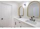 Bathroom with double sinks, white cabinets, black hardware, and gold-trimmed mirrors at 1006 Blue Lantern Dr, Henderson, NV 89015