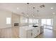 Open-concept living room featuring a kitchen island with sink and modern light fixtures, fireplace with stone accent wall, and windows at 1006 Blue Lantern Dr, Henderson, NV 89015