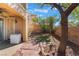 Backyard area featuring a brick patio, synthetic grass, and mature trees at 1059 Via Saint Lucia Pl, Henderson, NV 89011