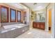 Bathroom featuring a luxurious soaking tub, vanity, and natural light from plantation shutters at 1059 Via Saint Lucia Pl, Henderson, NV 89011