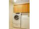 Bright laundry room with a front load washer and dryer and wooden cabinets above at 11204 Newbury Hills Ave, Las Vegas, NV 89138