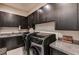 Modern laundry room with dark wood cabinets, granite countertop, and stainless steel washer and dryer at 11296 Villa Bellagio Dr, Las Vegas, NV 89141