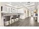 Bar area boasts white cabinets, glass shelves, grey countertop, mini-fridge, backsplash, and three stools at 12217 Tempestad Ave, Las Vegas, NV 89138