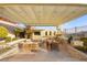 Outdoor kitchen featuring a dining table, grill, tv, and cozy seating beneath a stylish pergola at 12217 Tempestad Ave, Las Vegas, NV 89138