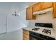 Bright kitchen featuring gas stovetop, wooden cabinets, and tile floors with stairs and door in background at 2049 Audrey Hepburn St, Las Vegas, NV 89142