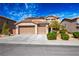 Charming two-story home featuring a three-car garage, manicured landscaping, and solar panels on the roof at 2176 De Narvik Dr, Henderson, NV 89044