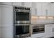 Close up of stainless steel double ovens and a microwave in a kitchen with white cabinets at 2176 De Narvik Dr, Henderson, NV 89044