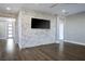 Living room with a brick wall, a TV, and hardwood floors at 2176 De Narvik Dr, Henderson, NV 89044