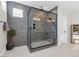 Bathroom with glass-enclosed shower featuring gray tile, a small bench seat and pebble flooring at 2493 Verdello St, Henderson, NV 89044