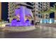 Exterior view of a modern high-rise building entrance with water feature and palm trees at night at 2700 Las Vegas Blvd # 1604, Las Vegas, NV 89109