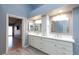 Modern bathroom featuring double sinks, white cabinets, a large mirror, and light wood flooring at 3109 Bangor Ct, Las Vegas, NV 89134