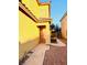 A yellow house has a security door, decorative gate and a desert landscape at 3438 Ceremony Dr, Las Vegas, NV 89117