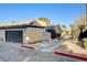 View of townhomes featuring assigned garages and stucco exteriors, complemented by manicured landscaping and sidewalk at 4648 Comnor Hill Ln, Las Vegas, NV 89121