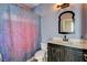 This bathroom has a sink with cabinet, toilet, decorative shower curtain, and a classic light fixture at 5827 Delonee Skies Ave, Las Vegas, NV 89131