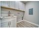 Bright laundry room features gray wood-look flooring, white cabinets and quartz counters at 6360 Montclair St, Pahrump, NV 89061