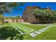 Large backyard featuring a bocce ball court, grass, trees, and patio lighting at 6391 Tempting Choice Ave, Las Vegas, NV 89131
