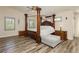 Primary bedroom featuring luxury four poster bed, wood floors, and window shutters at 6391 Tempting Choice Ave, Las Vegas, NV 89131