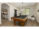 Game room with a pool table is illuminated by a chandelier and accented by bright windows with shutters at 6391 Tempting Choice Ave, Las Vegas, NV 89131