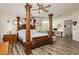 Spacious primary bedroom featuring a four-poster bed, ceiling fan, and wood-look flooring at 6391 Tempting Choice Ave, Las Vegas, NV 89131