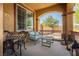 Covered front porch with cozy seating area including metal chairs, table, and blue cushioned loveseat at 6391 Tempting Choice Ave, Las Vegas, NV 89131