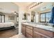 Bathroom with double sinks, granite counters, wood cabinets, and an arched doorway leading to the bedroom at 6629 Breakwater Reef St, Las Vegas, NV 89149