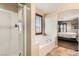 Modern bathroom featuring a glass-enclosed shower, separate bathtub, and an archway to a spacious bedroom at 6629 Breakwater Reef St, Las Vegas, NV 89149