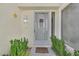 Well-maintained front entrance features a screen door, a wall light and lush landscaping at 6959 Emerald Springs Ln, Las Vegas, NV 89113