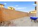 The gravel backyard features a table covered in blue tarp next to the block wall dividing properties at 6989 Walden Park St, Las Vegas, NV 89166