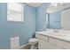 Cozy bathroom with blue walls, white fixtures, and a window providing natural light at 7020 English Mist Cir, Las Vegas, NV 89128