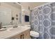 Well-lit bathroom featuring a vanity sink, toilet, and patterned shower curtain at 7632 Amato Ave, Las Vegas, NV 89128