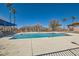 Community pool and lounge area on a sunny day with surrounding palm trees and fencing at 7632 Amato Ave, Las Vegas, NV 89128