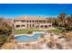 Expansive backyard featuring a sparkling pool with rock accents, patio, manicured lawn, and elegant two-story home at 9631 Orient Express Ct, Las Vegas, NV 89145