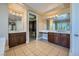 Dual vanities, custom mirrors, and dark wood cabinets complement the tile flooring in the spacious main bathroom at 10332 Sweet Laurel St, Las Vegas, NV 89178