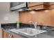 Modern kitchen featuring a stainless steel sink, black countertops, and a microwave with a mounted range hood at 135 E Harmon Ave # 1007, Las Vegas, NV 89109