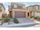 Tan two-story home with brick driveway and two-car garage, surrounded by desert landscaping at 354 Spotted Dove St, Las Vegas, NV 89138