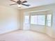 Bright living room area with large windows overlooking the backyard, ceiling fan and neutral carpet at 4695 E Lucera Ct, Pahrump, NV 89061