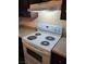 A white stove with 4 burners and hood with dark brown cabinets and light counter tops at 4708 Thunderbolt Ave, Las Vegas, NV 89115