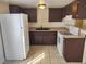 Kitchen with a white refrigerator, dark cabinets, and tile flooring at 4708 Thunderbolt Ave, Las Vegas, NV 89115