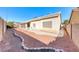 Wide angle shows desert-landscaped backyard with brick-lined planter, covered patio, and concrete at 1035 Dodger Blue Ave, Las Vegas, NV 89123