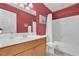 Bathroom with a shower, red accent wall, white cabinets and ample lighting at 10725 Wrigley Field Ave, Las Vegas, NV 89166